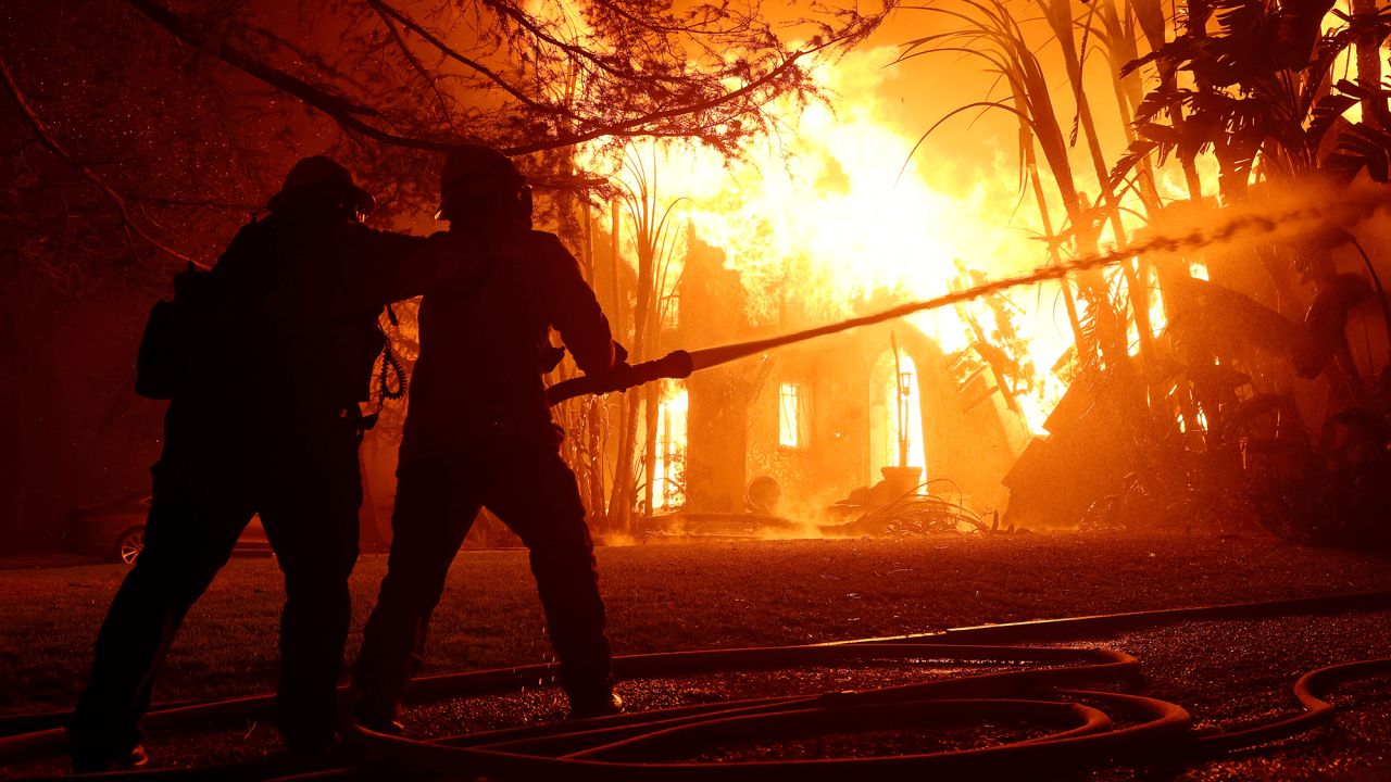 Los Angeles County firefighters spray water on a burning home as the Eaton Fire moved through the area on January 08, 2025 in Altadena, California. Fueled by intense Santa Ana Winds, the Palisades Fire has grown to over 2,900 acres and 30,000 people have been ordered to evacuate while a second fire has emerged near Eaton Canyon in Altadena.