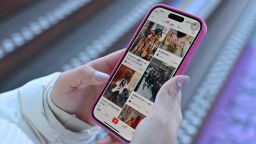 A photo illustration shows a woman holding her smartphone displaying the Chinese social networking and e-commerce app Xiaohongshu, also known as RedNote, in Beijing on January 15, 2025.