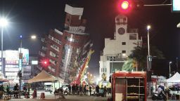Emergency personnel stand in front of a partially collapsed building leaning over a street in Hualien on April 3, 2024, after a major earthquake hit Taiwan's east.